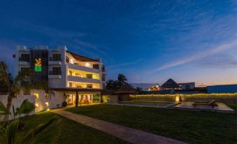 a building with a green lawn in front of it , lit up at night , and a sailboat docked nearby at Hotel Rio Lagartos