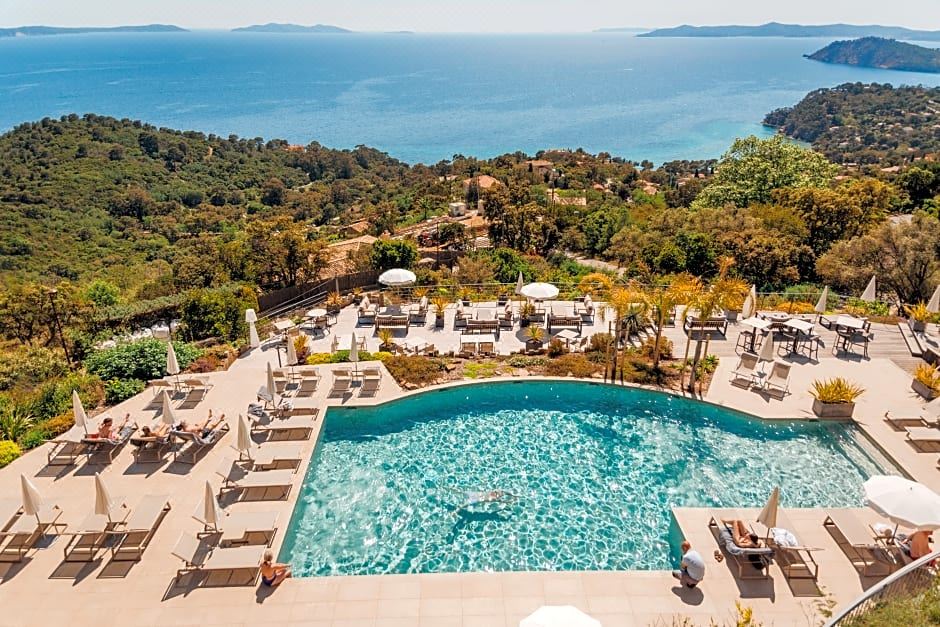 a large swimming pool surrounded by umbrellas and lounge chairs , with a view of the ocean in the background at Hotel la Villa Douce