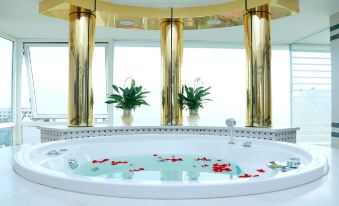 a large bathtub filled with water and rose petals is surrounded by tall gold columns at Green Hotel