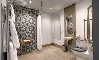 a modern bathroom with a gray and white patterned shower curtain , a toilet , and a sink at The Temple Inn