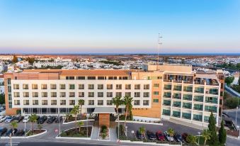 aerial view of a large hotel building surrounded by palm trees , with a city in the background at AP Maria Nova Lounge