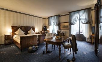 a hotel room with two beds , a dining table , and chairs , as well as a suitcase on the floor at Grandhotel Giessbach