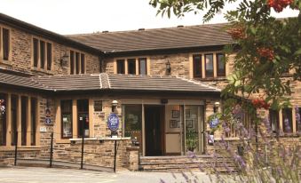 a brick building with a stone facade and two windows , located in a residential area at Best Western Bradford Guide Post Hotel