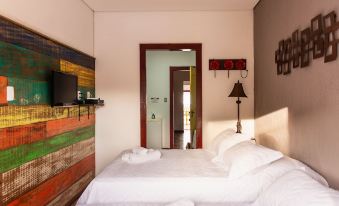 a bedroom with a white bed and a red wall , next to a red door at Pousada Tesouro de MInas