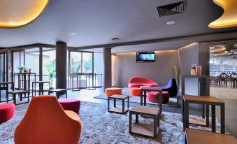 a modern lounge area with colorful chairs , tables , and a tv mounted on the wall at The Gate Hotel