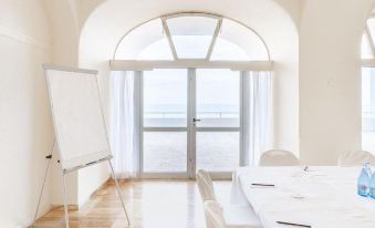 a large , empty room with wooden floors and white walls , featuring a whiteboard on the left side , a table with white chairs , and a at Precise Resort Tenerife
