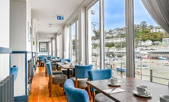 a dining room with blue chairs and tables , along with a view of the water at Portbyhan Hotel