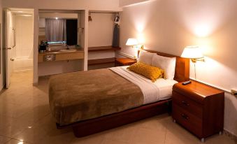 a bed with a brown blanket and white pillows is in a room with two lamps at Solace by the Sea