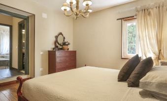 a large bedroom with a king - sized bed and a chandelier hanging from the ceiling , creating a cozy atmosphere at Piero