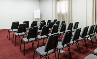 a conference room with rows of chairs arranged in a semicircle , and a projector on the wall at Ibis Styles Birigui