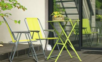 a table and two chairs on a patio , with a potted plant in the background at Cléome