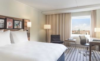 a hotel room with a large bed , white linens , and a view of the city at Radisson Blu Scandinavia Hotel, Aarhus