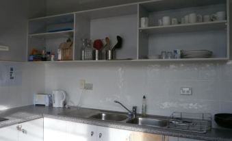 a kitchen sink is visible in the foreground , with shelves above it displaying various items at Waterfront Lodge Motel