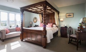 a large wooden bed with a canopy is in a bedroom next to a window at Blaisdon House B&B