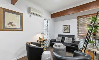 a modern living room with black leather couches , a coffee table , and an air conditioner on the ceiling at Blue Shades Motel