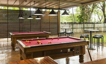 a pool table with red felt is set up in an outdoor area with hanging lights at Albatross Bay Resort