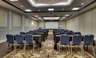 a large conference room with rows of chairs arranged in a semicircle , and a projector screen mounted on the wall at The Inn at Wise