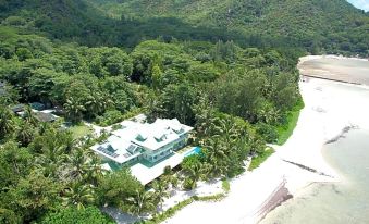 aerial view of a large house surrounded by trees and mountains , located on a beach at Palm Beach Hotel