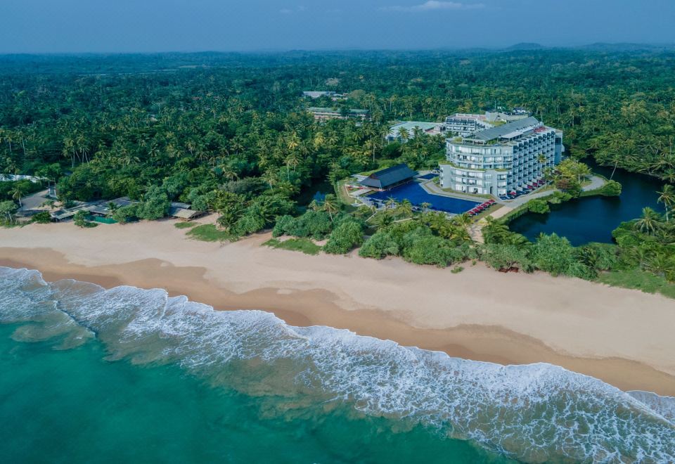a luxurious beachfront resort with a pool and restaurant , surrounded by lush greenery and clear blue water at Sheraton Kosgoda Turtle Beach Resort