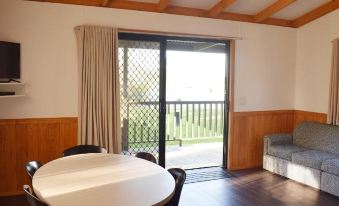 a dining room with a wooden table and chairs , and a sliding glass door leading to a balcony at Cohuna Waterfront Holiday Park