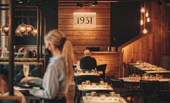 a restaurant interior with wooden walls , dimly lit dining tables , and a waitress serving customers at Hope Street Hotel