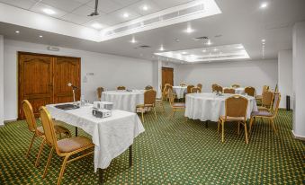 a large , empty conference room with white tables and chairs set up for a meeting or event at Grand Hotel Madaba