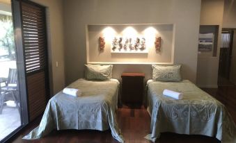 a room with two twin beds , one on the left and one on the right side of the room at Mangaia Villas