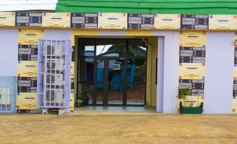 a small building with a yellow and green exterior , doors on either side , and a metal gate at Hotel Lewi