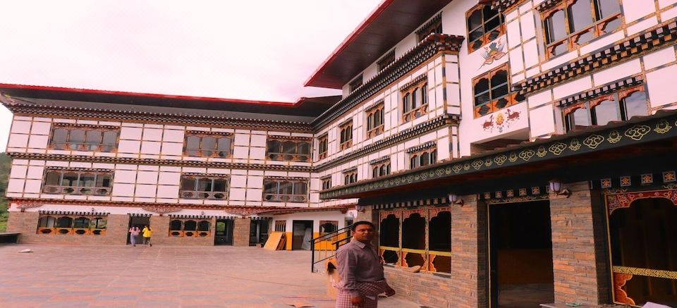 a person is standing in front of a large building with many windows and doors at Hotel River Valley