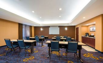 a conference room with rows of tables and chairs , a projector screen , and a large screen on the wall at Sonesta Select Detroit Novi