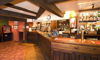 a bar with wooden furniture and a red carpet , along with various bottles on the counter at Premier Inn Tring