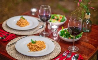 a dining table with two plates of food , two wine glasses , and a bowl of salad at Hacienda San Miguel Yucatan