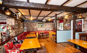 a cozy restaurant with wooden tables , booths , and benches , as well as red cushions on the tables at Old Posting House