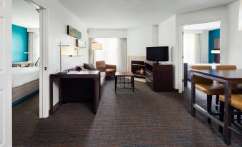 a hotel room with a fireplace , flat - screen tv , couch , and dining table , all in modern style at Residence Inn Provo North