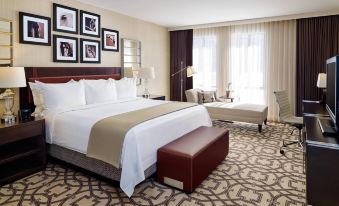 a large bed with white linens and a beige blanket is in the middle of a room with framed pictures on the wall at Delta Hotels by Marriott Baltimore Hunt Valley
