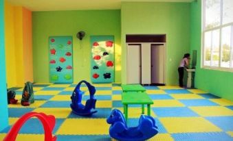 a brightly colored indoor play area with various toys , including swings , a slide , and a climbing wall at Sepon Boutique Resort