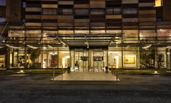 a modern building with a glass entrance and large windows , lit up at night , under a clear sky at Hotel Cruise