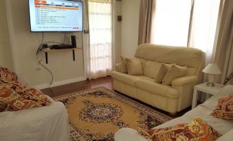 a living room with a beige couch , brown rug , and a large screen on the wall at Sailors Rest