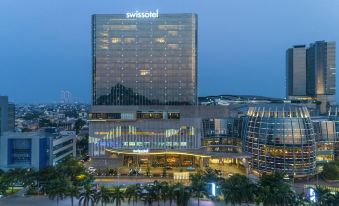 "a large , modern building with a glass facade and the words "" swissotel "" prominently displayed on it" at Swissôtel Jakarta PIK Avenue