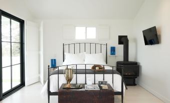 a white bedroom with a black metal bed , a wood stove , and a vase on the nightstand at The Lakeside Motel