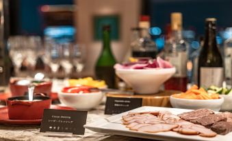 a dining table with a variety of food and drinks , including a plate of ham and bottles at The Royal Park Hotel Iconic Osaka Midosuji
