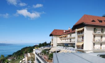 a hotel with a large balcony overlooking the ocean , surrounded by trees and a blue sky at Le Mirador Resort and Spa