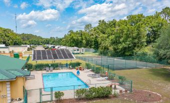 a swimming pool surrounded by a sports field , with several people enjoying their time in the pool at Magnuson Hotel Wildwood Inn Crawfordville