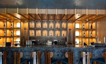 a modern bar with wooden walls , blue marble countertop , and various bottles of liquor on display at The Manor - New Delhi