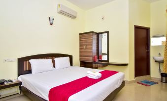a large bed with a white and red blanket is in a room with yellow walls at OYO Flagship Hotel Priso