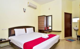 a hotel room with a double bed , a dresser , and a tv . also a bathroom visible in the room at OYO Flagship Hotel Priso