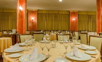 a well - decorated dining room with multiple tables set for a formal dinner , including wine glasses , plates , and napkins at Hotel Zodiaco