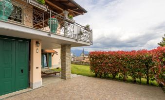 a brick house with a green door and a balcony , surrounded by lush vegetation and flowers at Federica