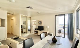 a modern living room with a dining table , chairs , and a flat - screen tv . also a couch in the room at Milson Serviced Apartments
