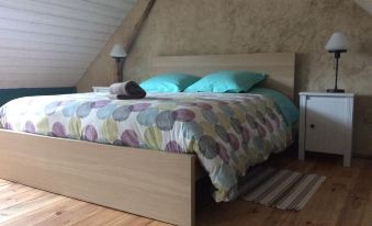 a bed with a wooden headboard and blue pillows is placed in a room with a slanted ceiling at La Vieille Ferme